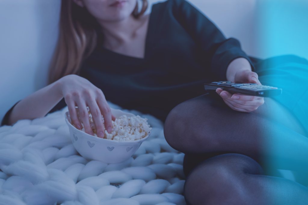 Woman In White Bed Holding Remote Control While Eating