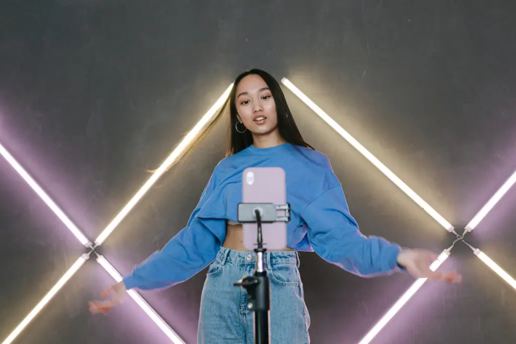 A Woman In Blue Sweater Dancing In Front Of Her Mobile Phone On A Tripod