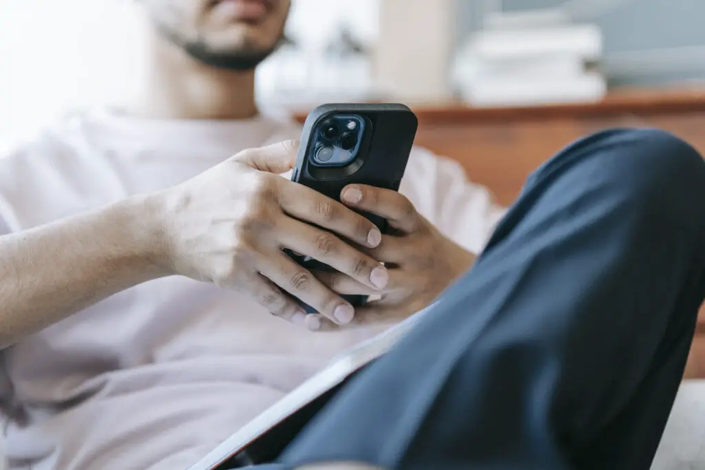 Crop Bearded Man Using Smartphone In Living Room